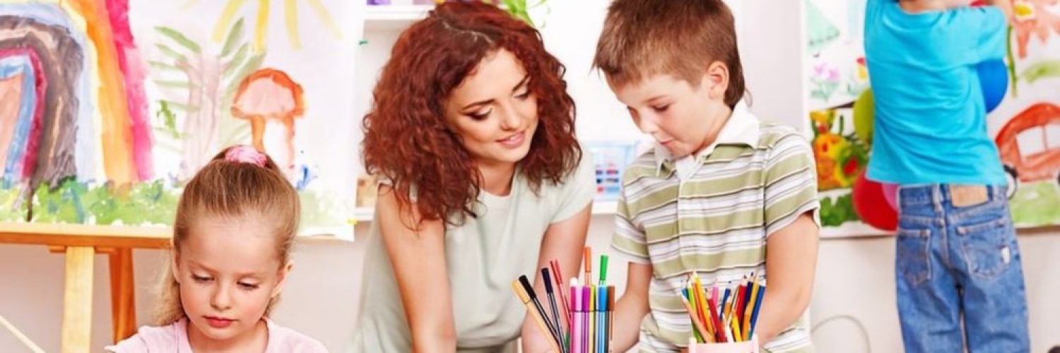 classer3 In einem farbenfrohen Klassenzimmer in einer christlichen Gesamtschule malt eine Gruppe junger Kinder an einem Tisch. Eine Frau beugt sich zu ihnen hinüber, um ihnen zu helfen, während im Hintergrund Regale mit Malutensilien und Kinderbildern den Raum mit kreativer Inspiration füllen.